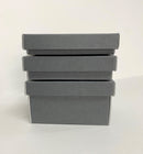 A stack of three small gray artifact boxes with lids, made of conservation board, designed for holding small delicate objects.