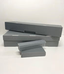 A set of gray custom-made boxes of various sizes, made from archival materials, displayed flat on a white surface.